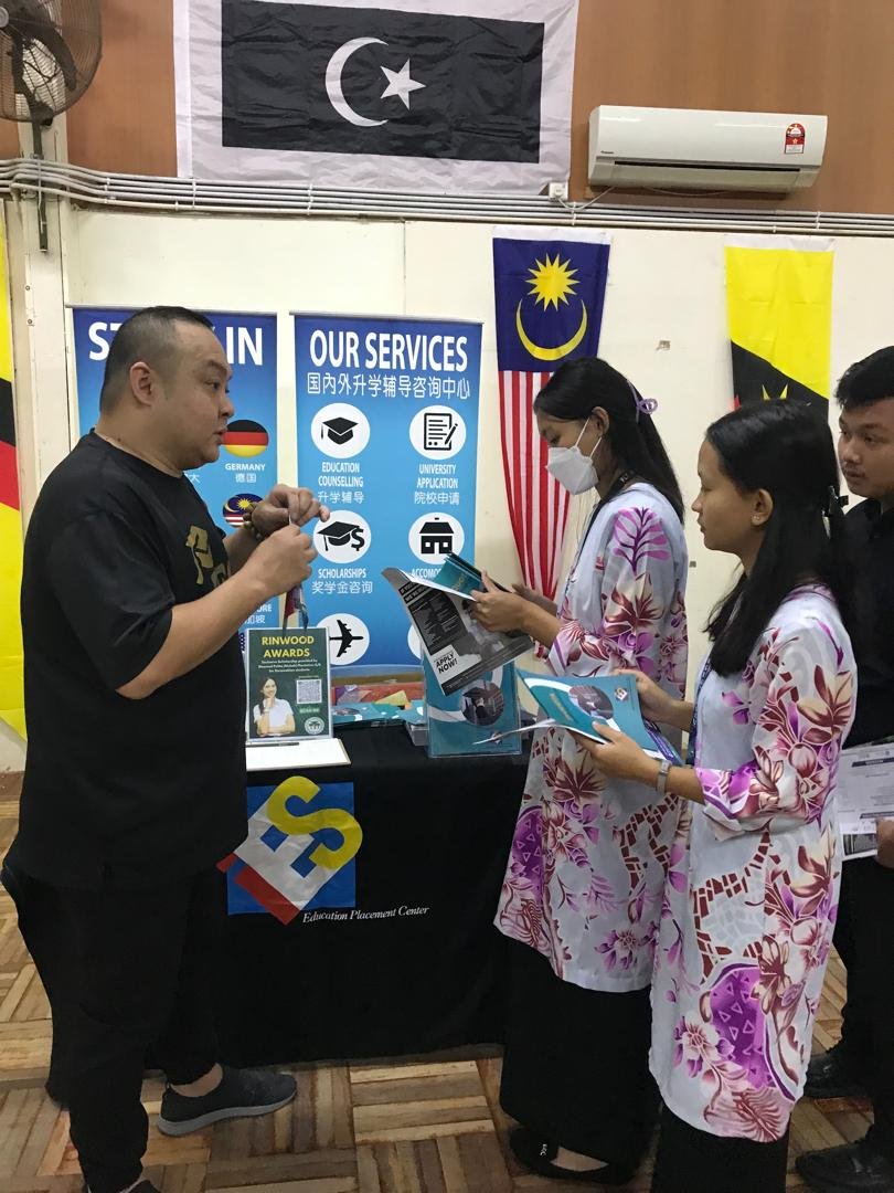 Prospective students interacting with staff at university admission booth