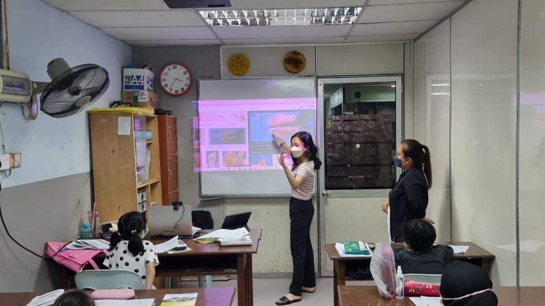English teacher presenting a lesson with a projector to junior students in a classroom at PTMJ